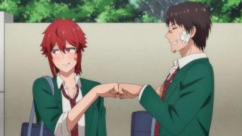 Tomo-chan Is a Girl! TV Show: A high school boy and girl fist bump each other, the girl looks away blushing while smiling, the boy grins with his eyes closed.