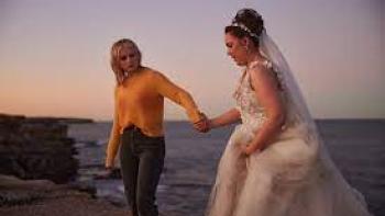 Totally Completely Fine TV show: A woman in a wedding dress stands outside holding hands with a woman wearing jeans and a sweater.