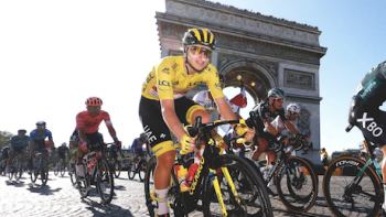 Tour de France: Unchained TV show screenshot 3: Cyclists in red, blue, and white jerseys ride by the Arch de Triomphe