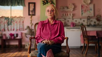 Trust Me: The False Prophet TV show screenshot: Christine Katas sits on a chair in her colorful cottage