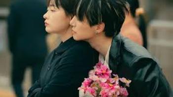 Typhoon Family TV show screenshot #2: A young Korean man looks over the shoulder of a young Korean woman; he holds flowers