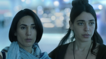 Unconditional TV show screenshot 1: Two women in a blue-tinted environment, looking serious.