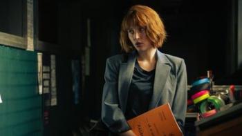 Under a Dark Sun TV show screenshot 2: A young, redheaded woman with a bob haircut and professional looking gray suit, stands holding papers