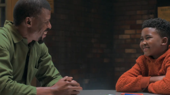 Unseen TV show screenshot 3: Raymond sits at a table talking to Esulu.