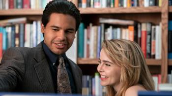 Up Here TV show: Lindsay and Miguel are shown in from the shoulders up in a bookstore, standing close together; they look to be flirting