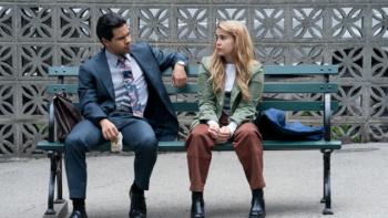 Up Here TV show: Lindsay and Miguel sit together on a city bench with a concrete wall behind them; they appear to be talking happily together