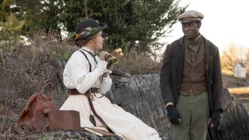 Iola Evans and Ernest Kingsley Junior. Evans wears a white dress. Junior wears green pants, a brown waistcoat, and black coat.