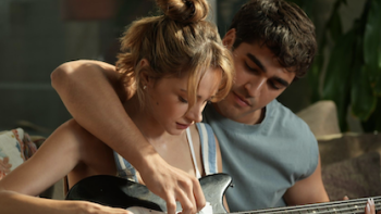 We'll Be Fine TV show screenshot 1: A woman and man playing guitar together on a sofa, focused and relaxed.
