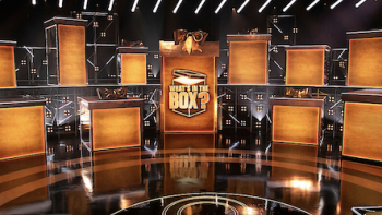 What's in the Box TV show screenshot 1: Series set with large gold boxes.
