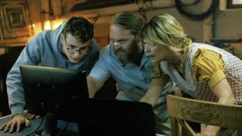 (From left to right) Leo Simon, Axel Stein, and Heike Makatsch lean onto a desk and peer into a computer monitor.