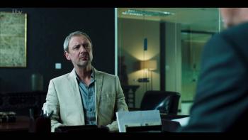 White Dragon Series: Jonah (John Simm) sits behind a desk