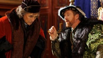Wolf Hall: The Mirror & the Light TV show screenshot 1: Thomas Cromwell and King Henry VIII speak together with Henry on his throne.
