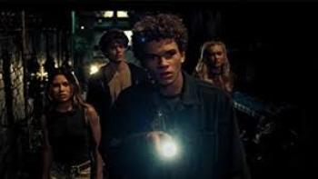 Wolf Pack TV show: Four young adults, two boys and two girls, peer forward from the dark using a flashlight.