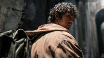 Wonderboys The Secret Treasure of Naples TV: Toni wearing a brown jacket and a backpack, looks over his shoulder in a well-lit tunnel.