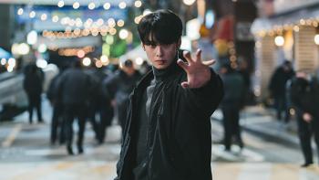 The Wonderfools TV show screenshot 3: A young man wearing black reaches his hand toward the camera on a busy city street at night.