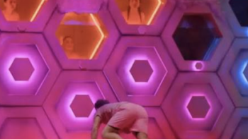 Wonka's The Golden Ticket TV show screenshot 3: A person crawling in a room with illuminated hexagonal panels.