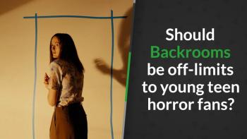 A woman stands in a shadowy room, casting a large shadow on the wall.