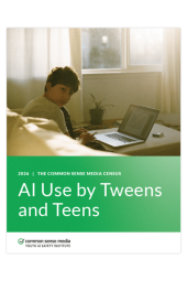 Tween aged boy with laptop looks over his shoulder 