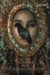 In My Mother's Skin movie poster: Filipino woman's face center has black bird in front of it while her entire head is surrounded by a large colorful bejeweled mask 