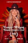 Lainey Wilson: Keeping Country Cool: Lainey poses in red jumpsuit and cowboy hat.