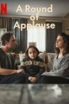 A Round of Applause TV show poster: A woman and man sit on a couch turned toward each other with their young son between them