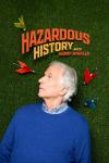Hazardous History with Henry Winkler: A man lays on some fake grass with darts by his white hair.