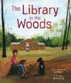 The Library in the Woods book cover: A log cabin library in a clearing in the woods; a young boy with dark skin sits on a tree stump, reads to dogs
